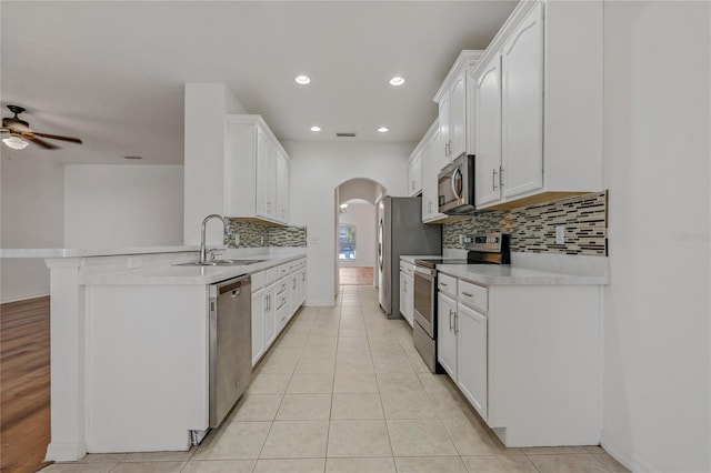 kitchen featuring appliances with stainless steel finishes, white cabinetry, sink, light tile patterned floors, and kitchen peninsula