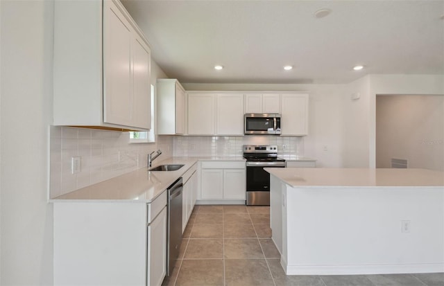 kitchen featuring appliances with stainless steel finishes, backsplash, sink, white cabinets, and light tile patterned flooring