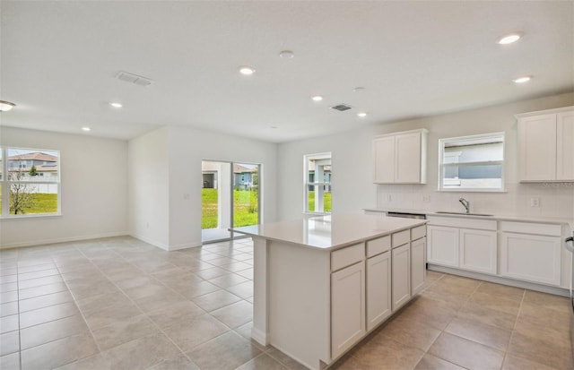 kitchen with a kitchen island, white cabinetry, sink, and a wealth of natural light