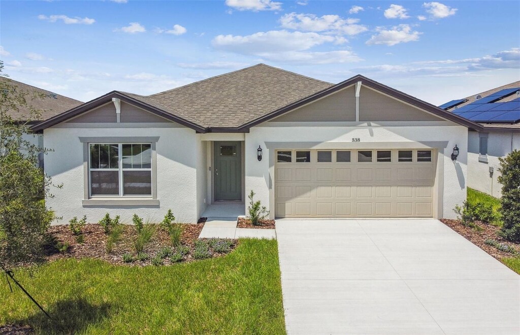 single story home featuring solar panels and a garage