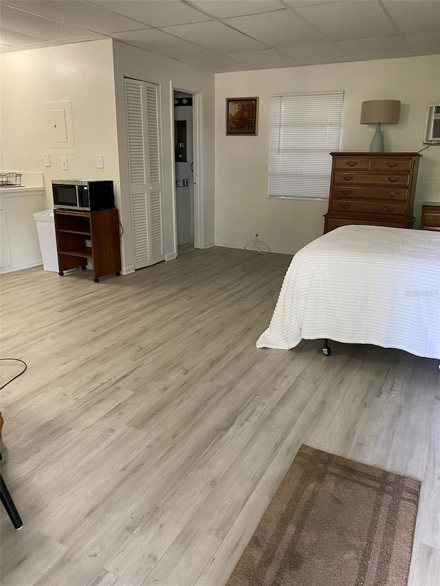 bedroom featuring a drop ceiling, light hardwood / wood-style floors, and connected bathroom