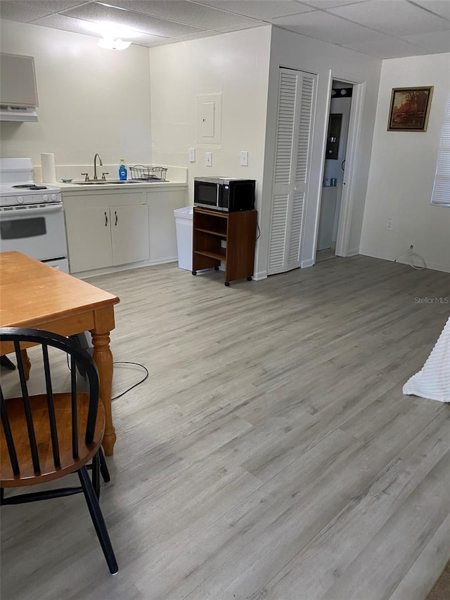 kitchen with white cabinets, light hardwood / wood-style flooring, sink, and range