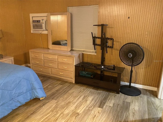 bedroom featuring wood walls, light hardwood / wood-style floors, and a wall mounted AC