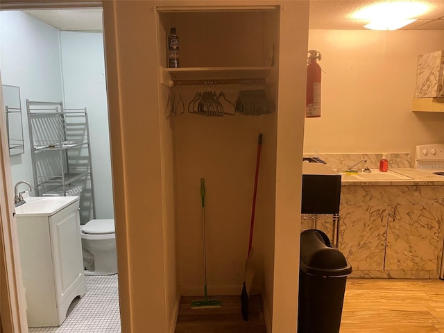 bathroom featuring vanity, hardwood / wood-style flooring, toilet, and washer / clothes dryer