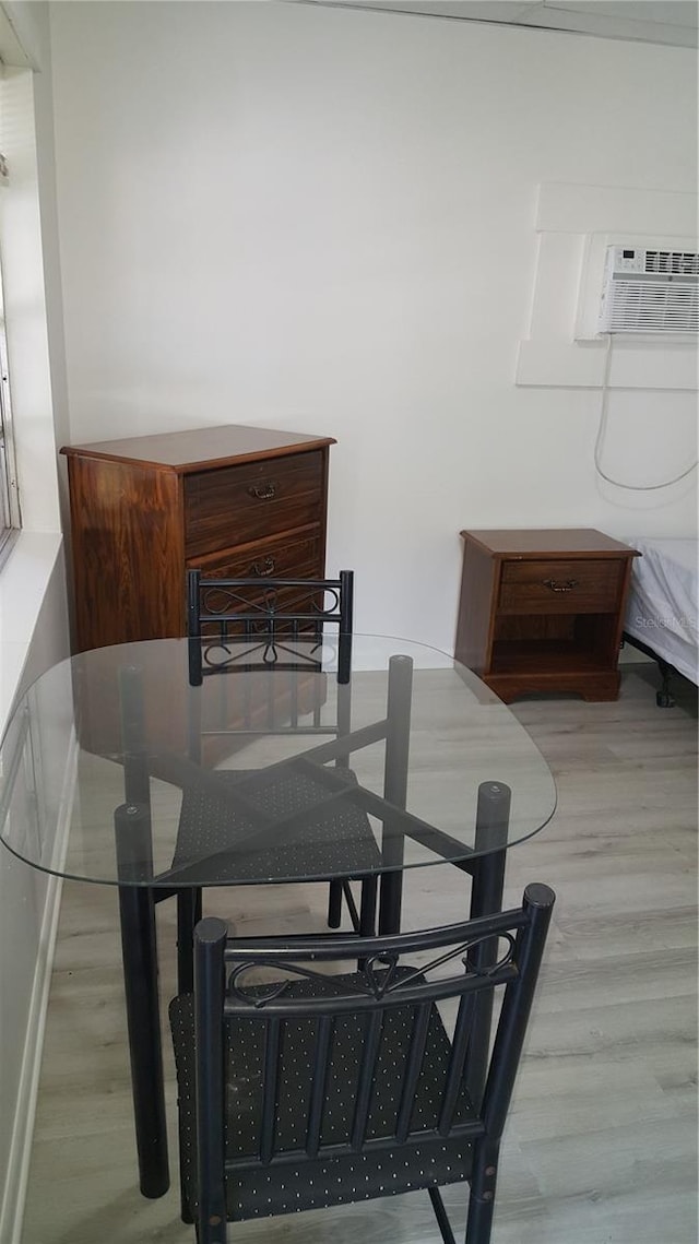 dining room with a wall mounted AC and light hardwood / wood-style floors