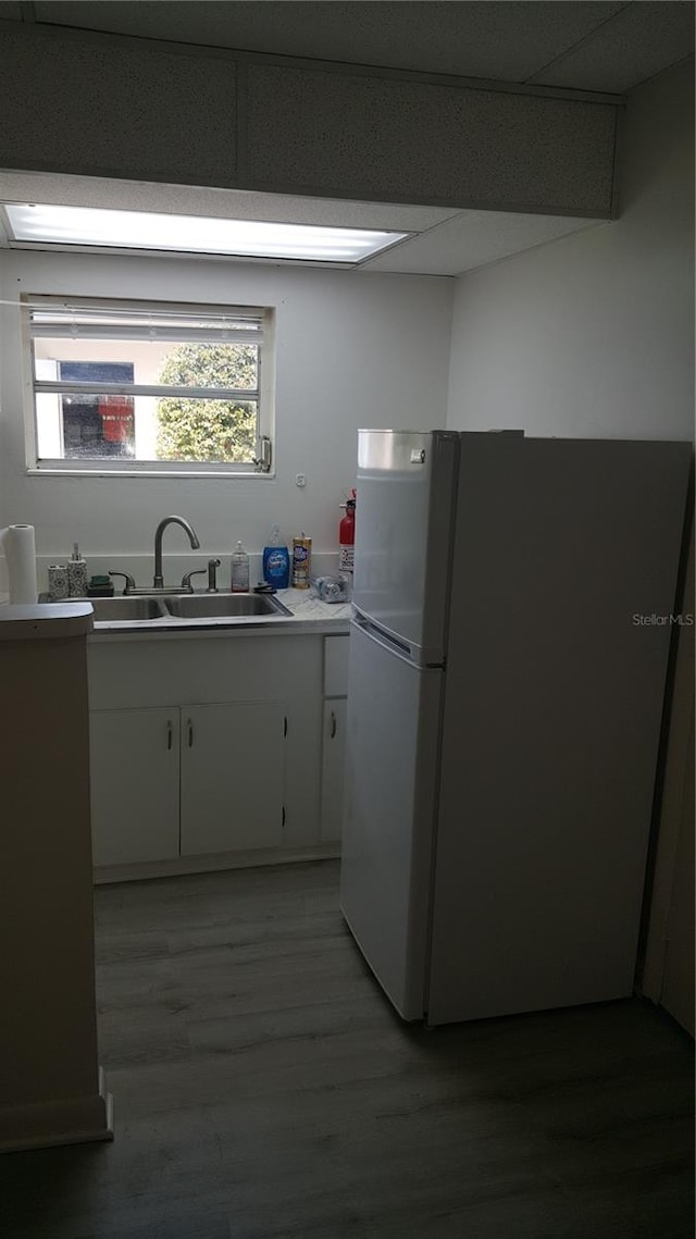 kitchen with white cabinets, sink, hardwood / wood-style flooring, and white fridge