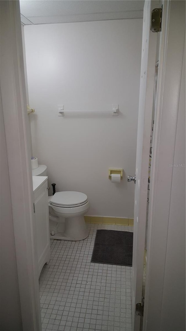 bathroom with toilet, tile flooring, and vanity