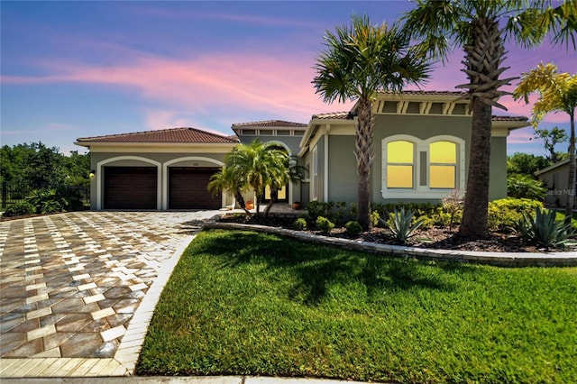 mediterranean / spanish-style home featuring a yard and a garage