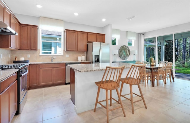 kitchen with a kitchen island, tasteful backsplash, stainless steel appliances, and light stone counters