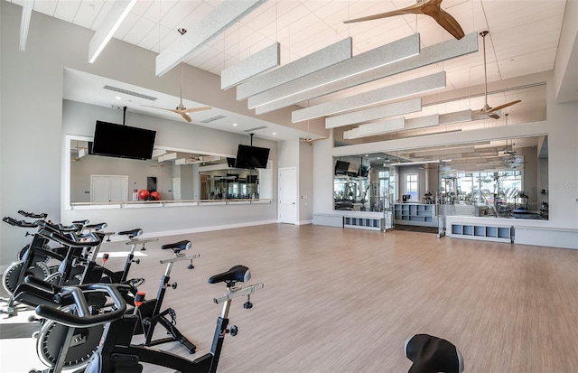 workout area featuring wood-type flooring, ceiling fan, and a high ceiling