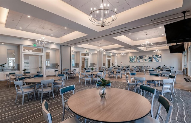 dining room with a chandelier, a raised ceiling, carpet floors, and coffered ceiling