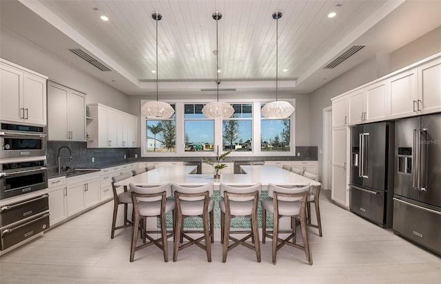 kitchen with a center island, decorative light fixtures, a breakfast bar, stainless steel appliances, and a raised ceiling