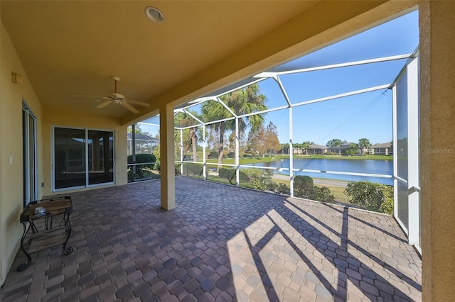 view of patio with glass enclosure, ceiling fan, and a water view