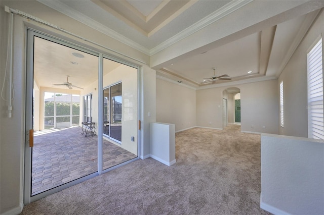 spare room featuring light carpet, a tray ceiling, ceiling fan, and crown molding