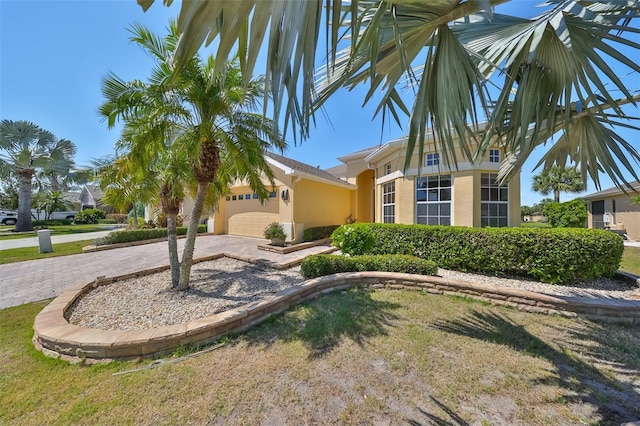 view of front of house with a garage, decorative driveway, and stucco siding