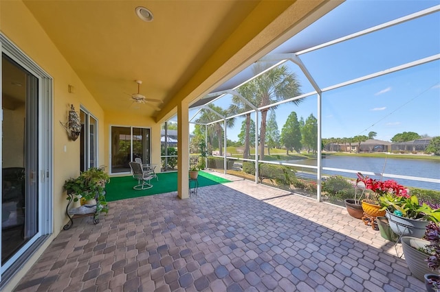 exterior space featuring a water view, glass enclosure, and a ceiling fan