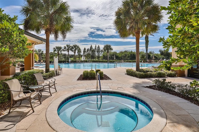 community pool with a hot tub and a patio