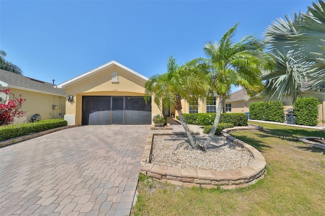 view of front facade featuring an attached garage, a front yard, decorative driveway, and stucco siding