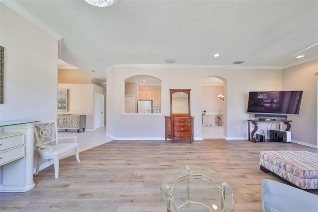 unfurnished living room featuring light wood finished floors, crown molding, arched walkways, and a textured ceiling