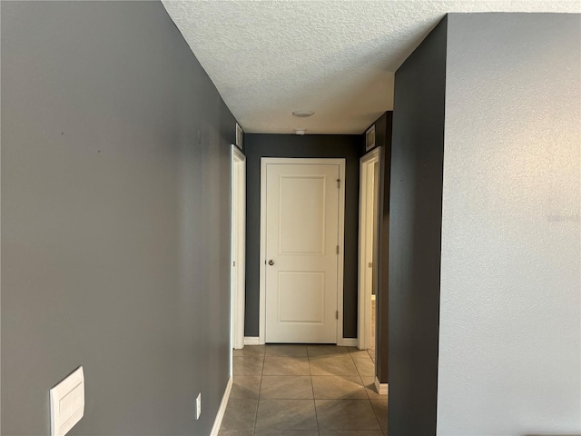 hallway with tile flooring and a textured ceiling