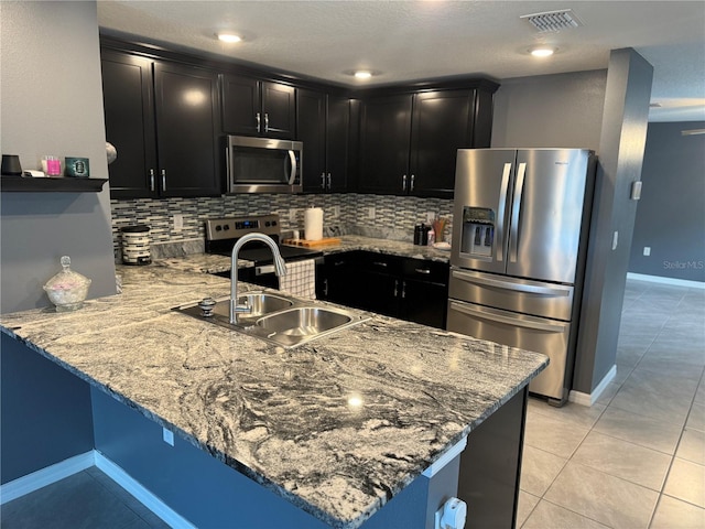 kitchen featuring kitchen peninsula, backsplash, stainless steel appliances, sink, and light tile floors