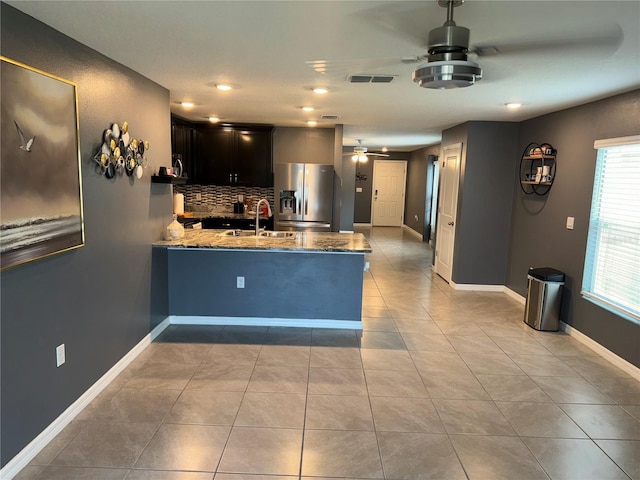 kitchen with stainless steel refrigerator with ice dispenser, backsplash, sink, light tile floors, and ceiling fan