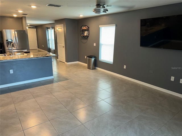 kitchen featuring stainless steel fridge, tile floors, and light stone countertops