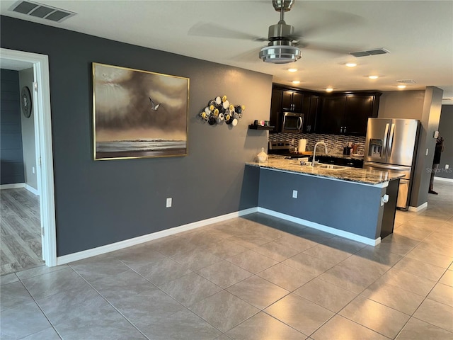 kitchen with light stone countertops, kitchen peninsula, appliances with stainless steel finishes, tasteful backsplash, and ceiling fan