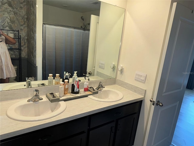 bathroom with wood-type flooring, vanity with extensive cabinet space, and double sink