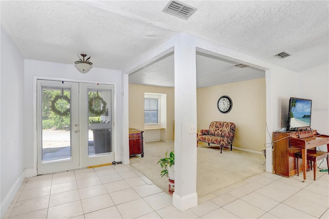 foyer with french doors, light tile flooring, and a textured ceiling