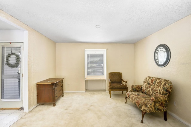 living area featuring light carpet and a textured ceiling