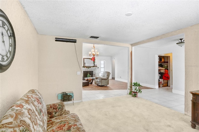 sitting room featuring a notable chandelier, a tile fireplace, light tile floors, and a textured ceiling