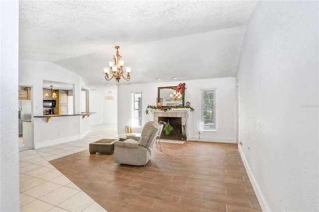 sitting room with vaulted ceiling, a tiled fireplace, tile flooring, a textured ceiling, and a chandelier