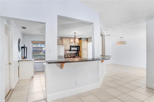 kitchen featuring a kitchen bar, stainless steel refrigerator, light tile floors, and pendant lighting