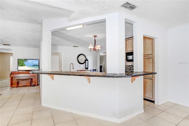 kitchen with a breakfast bar area, a notable chandelier, light tile floors, and stainless steel fridge