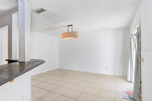 tiled empty room with a textured ceiling