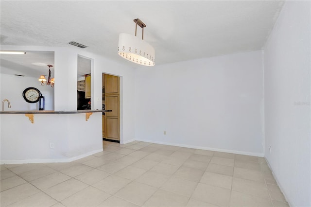 spare room featuring a chandelier and light tile flooring