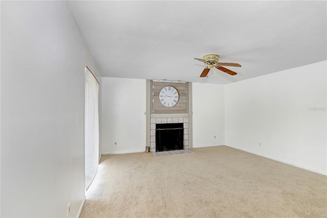 unfurnished living room featuring brick wall, light colored carpet, a tile fireplace, and ceiling fan