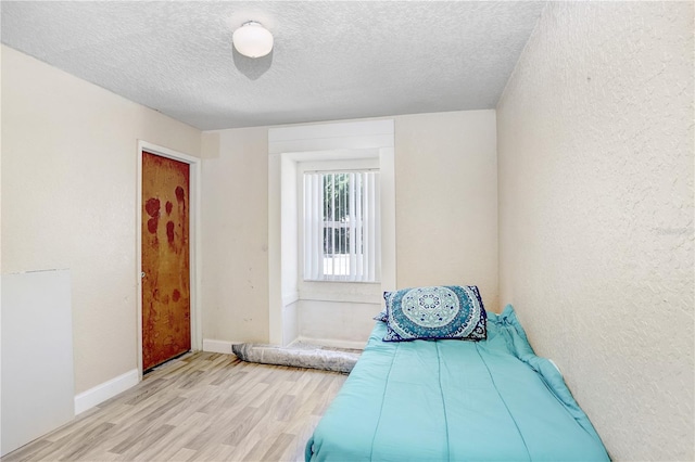 bedroom featuring light wood-type flooring and a textured ceiling