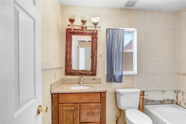 bathroom with tile walls, a bathing tub, vanity, and toilet