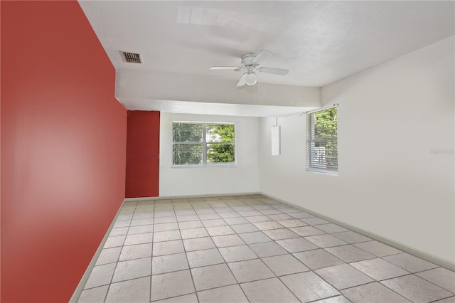 tiled empty room featuring plenty of natural light and ceiling fan