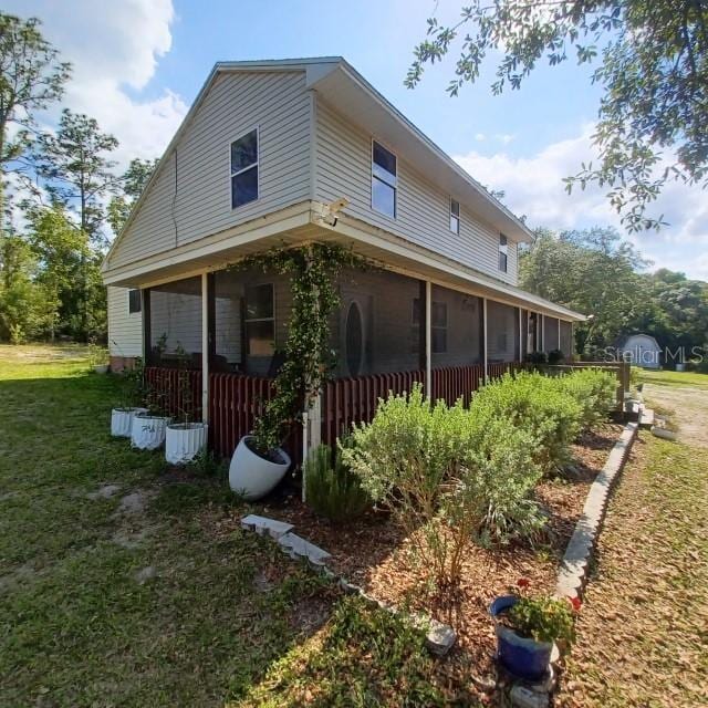 view of side of home featuring a lawn and a sunroom