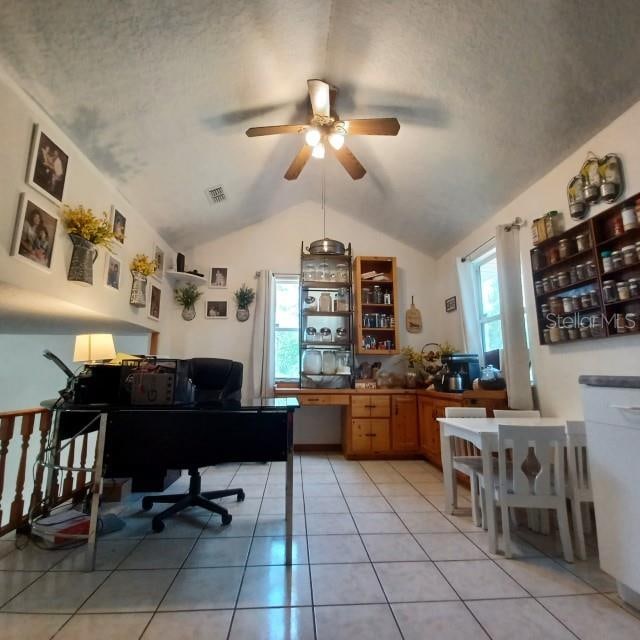 office with ceiling fan, a textured ceiling, lofted ceiling, and light tile patterned floors