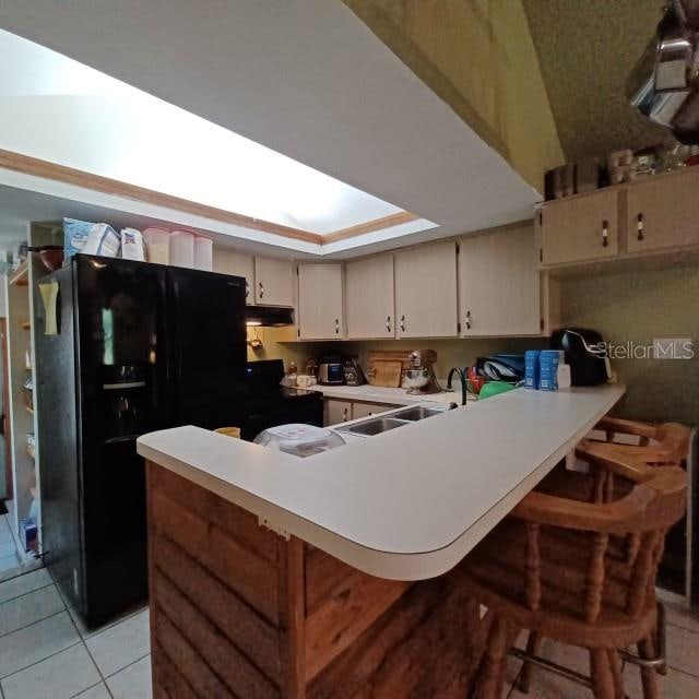 kitchen featuring kitchen peninsula, cream cabinets, a kitchen bar, and a skylight