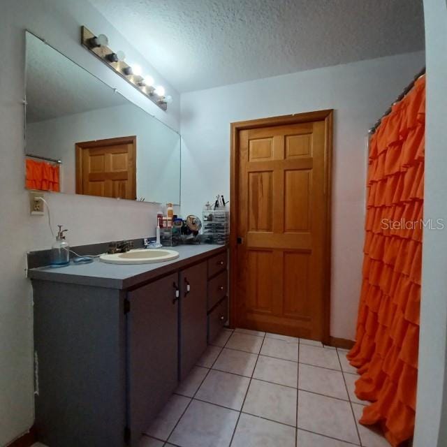 bathroom with a textured ceiling, vanity, and tile patterned floors