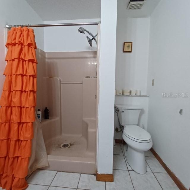 bathroom featuring a shower with curtain, toilet, and tile patterned floors