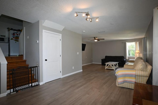 living area featuring a textured ceiling, dark hardwood / wood-style flooring, and ceiling fan