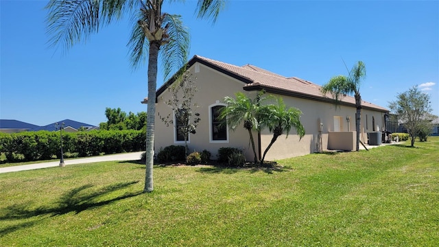 view of side of property with a lawn and central AC