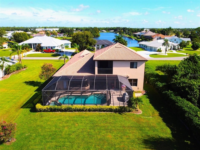 rear view of property featuring a lawn, a water view, and a lanai