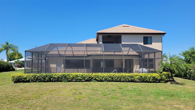 rear view of property featuring glass enclosure and a yard